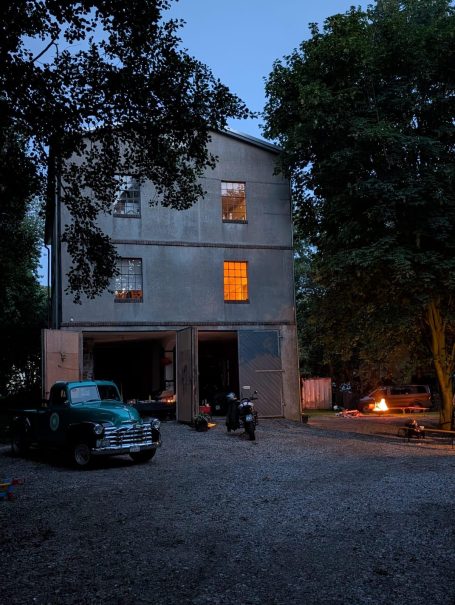 Inzwischen stecken Verlassenes Gebäude mit leuchtendem Fenster, Motorrad und Lagerfeuer im Vordergrund.
