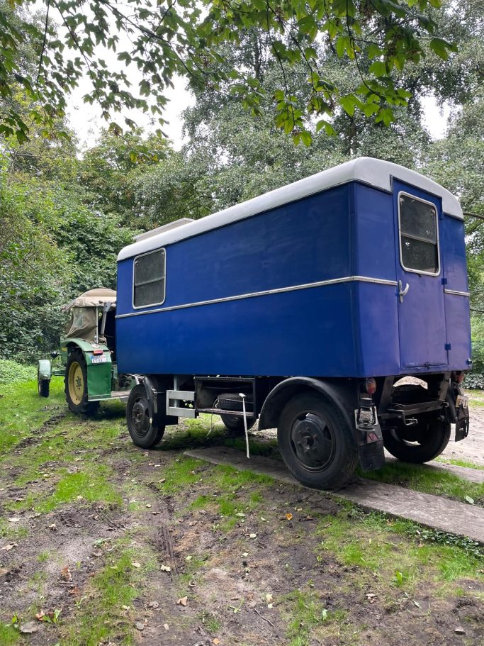 ...oder ein bisschen verrückt Blaues Wohnmobil steht neben einem grünen Traktor auf einer unbefestigten Straße.